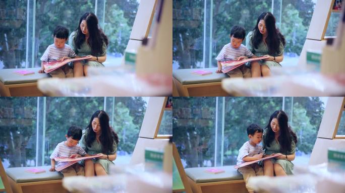 母亲和儿子坐在窗边一起读书