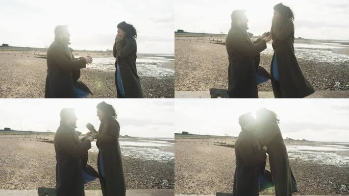 男子在阳光明媚的岩石冬季海滩向女友求婚
