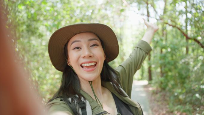 亚洲美女背包客vlogger独自在森林里旅行。迷人的女孩旅行者在假期旅行中使用手机记录视频日志，在自