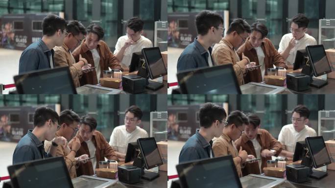 亚裔中国年轻男子在电影院等待电影放映时间时使用智能手机