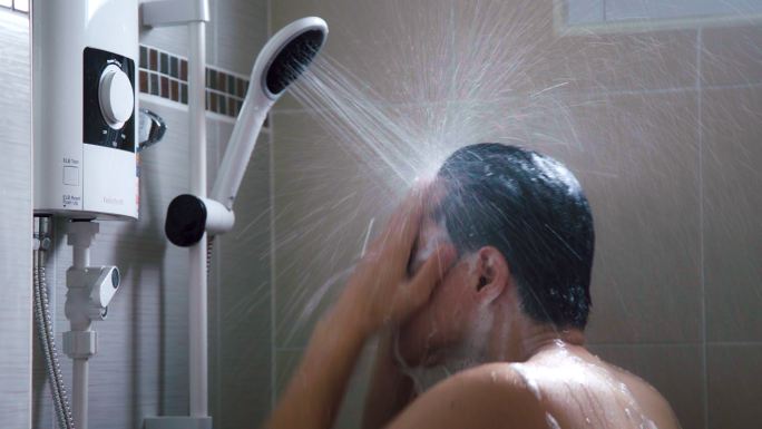 亚裔男子在浴室用淋浴器洗澡。在家洗澡的人的生活方式。特写镜头。