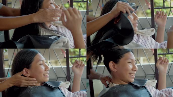 一个亚洲女孩躺在洗发水椅上，在妈妈面前洗头，生活方式理念。