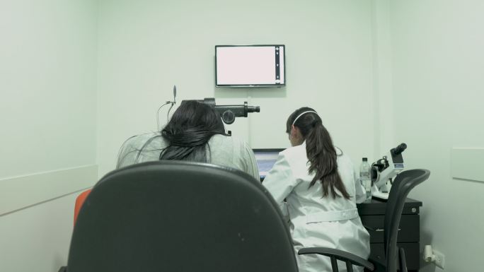 拉丁妇女，专业医生，用最先进的机器对患者进行目视检查