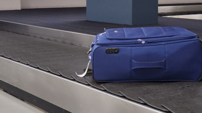 在机场行李提取区的行李传送带上移动的旅行包热
