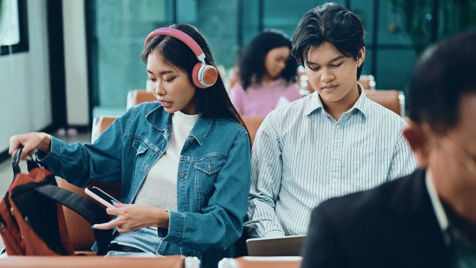 在休息室使用智能手机的亚洲大学生