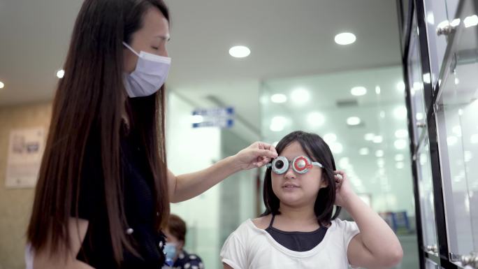 亚裔中国女性眼科医生在验光实验室与儿童患者使用试验框架。