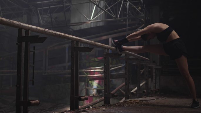 一个年轻的女性在一个废弃的健身房练习他的日常锻炼。