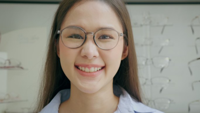 一位年轻女子戴着眼镜，在眼镜店开心地微笑的肖像。