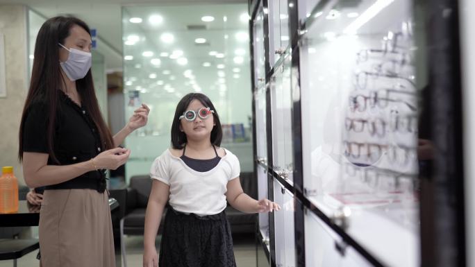 亚裔中国女性眼科医生在验光实验室与儿童患者使用试验框架。
