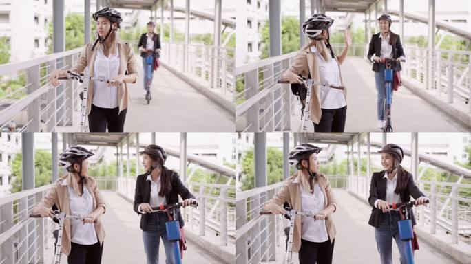 戴着头盔的亚洲美女正在驾驶滑板车过桥，在与手持自行车的同事会面后，她停止了骑行。两位女商人停下来，早