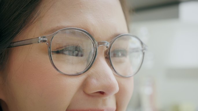 特写镜头：一位年轻女子戴着眼镜，在眼镜店开心地微笑。