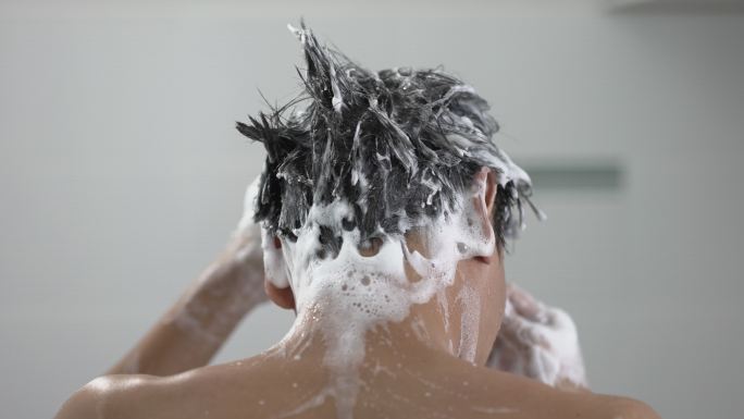 年轻人洗头，在浴室里用泡沫头淋浴