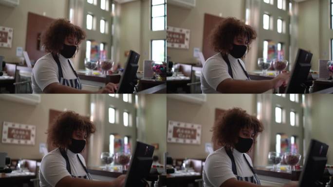 服务员在咖啡店的电脑上登记客户的订单-戴口罩