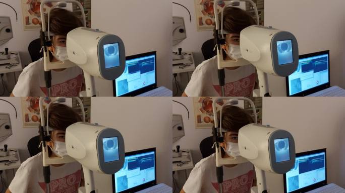 医生在诊所用现代设备检查一个男孩的视力。