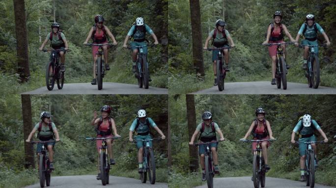 三名女子山地自行车手一起在树林中的一条铺好的道路上骑行