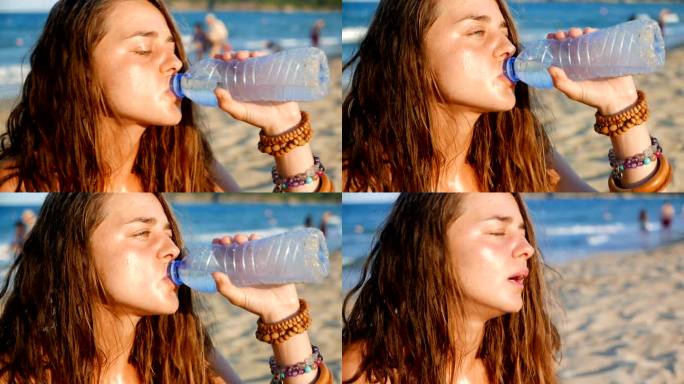 一个口渴的女孩在海滩上喝冷水的慢动作特写镜头