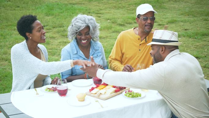 非裔美国人一家在野餐桌边聊天、喝酒