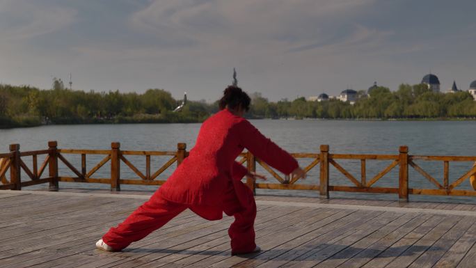一个女人在湖边练习太极拳。