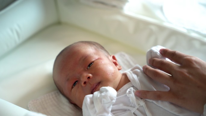 婴儿护理者用湿棉球清洁新生儿面部