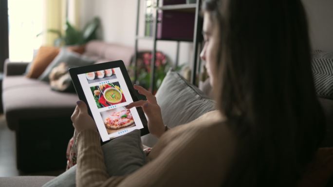女性通过数字平板电脑在线订购食物。