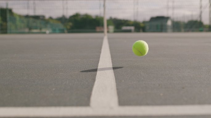 室外一个空网球比赛中，一个球在分界线上弹跳的4k视频片段