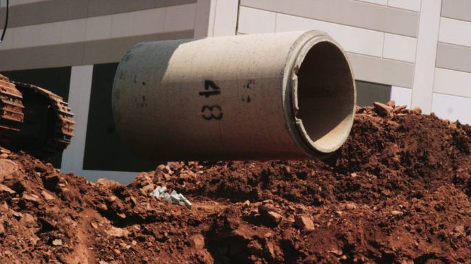 施工挖掘机在施工现场将钢筋混凝土管道吊入空中的慢镜头