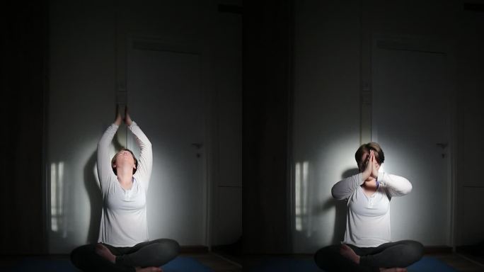 一位女士在她的公寓里练习瑜伽。日落时公寓的灯光效果。