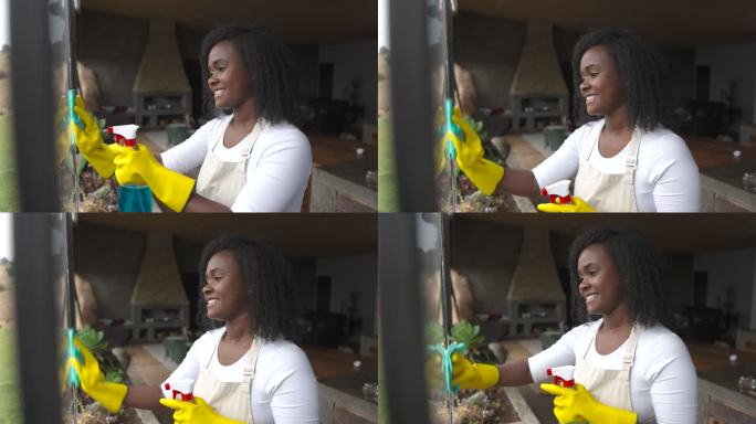 快乐的非裔美国妇女微笑着擦着窗户