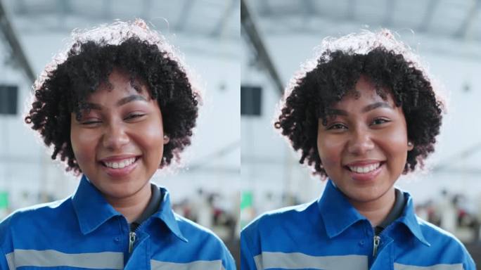 微笑着快乐的非洲裔美国女技术员工程师的垂直拍摄肖像穿着安全制服微笑着制造厂背景中的快乐工作环境