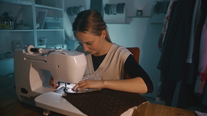 远景：一位年轻女裁缝在工作室使用缝纫机的肖像