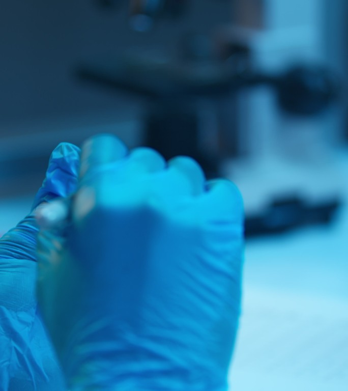 一个血液试管的特写镜头和一个戴着防护手套的实验室助理的手，在上面写了一个复选标记