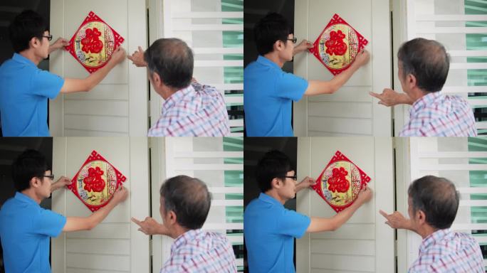 中国亚裔儿子和父亲在除夕用“财富”春联装饰家门