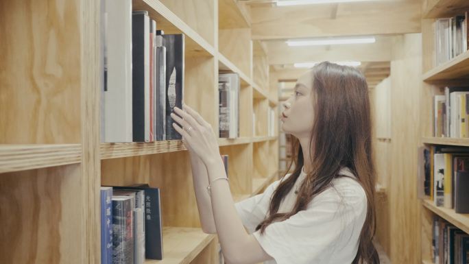 年轻的亚洲女大学生在图书馆找书（慢动作）