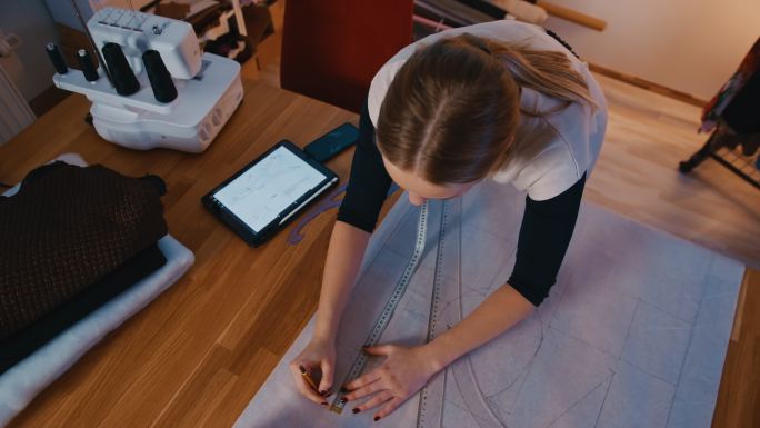 SLO MO年轻女裁缝在绘制未来面料产品的轮廓时使用数字平板电脑