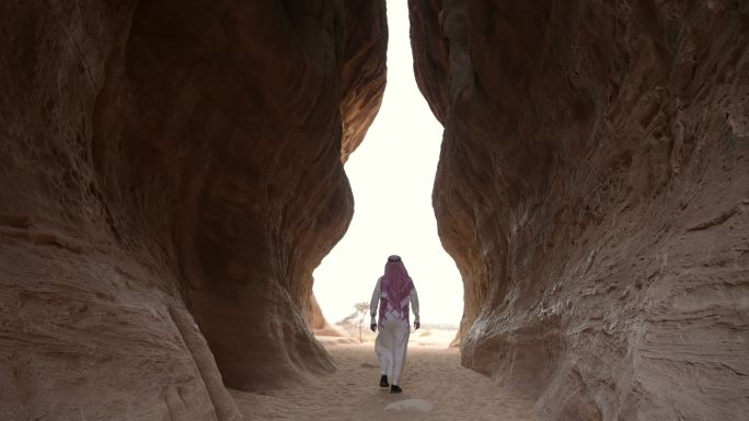 沙特男子穿过岩层之间的通道