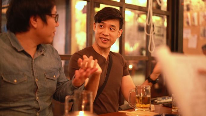 两名Asain男子在Izakaya日本酒吧餐厅喝啤酒聊天的三张照片