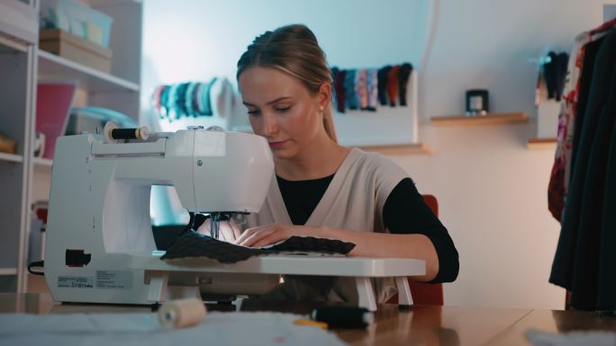 DS年轻女裁缝在工作室用缝纫机缝纫