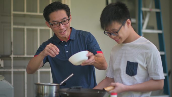 周末，亚裔中国父亲在潮湿的厨房后院教儿子做饭准备晚餐