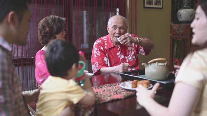 中国多代人在下午茶会期间在家享用传统中秋月饼和中国茶