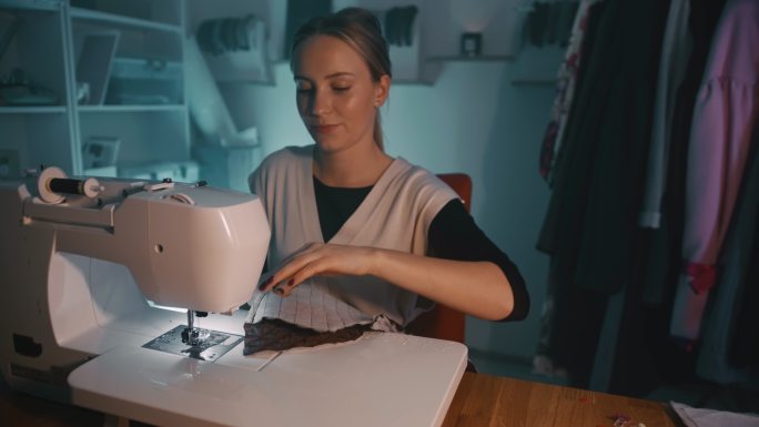 远景：年轻女裁缝在工作室用缝纫机缝纫