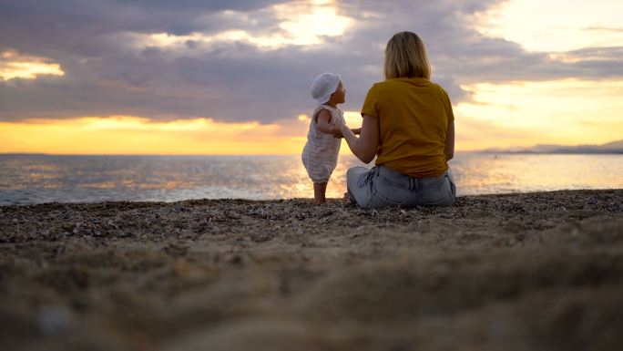 海滩上的年轻母亲和活泼的女婴