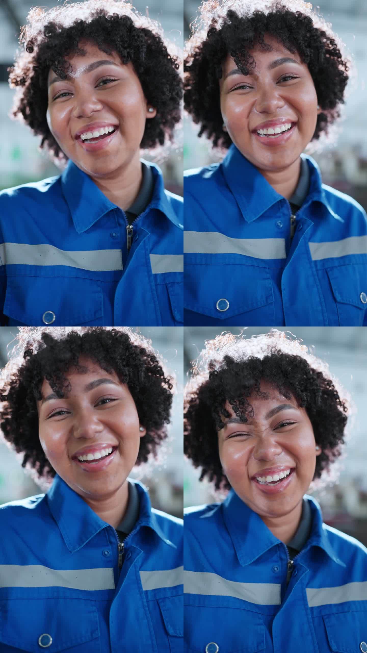 微笑着快乐的非洲裔美国女技术员工程师的垂直拍摄肖像穿着安全制服微笑着制造厂背景中的快乐工作环境
