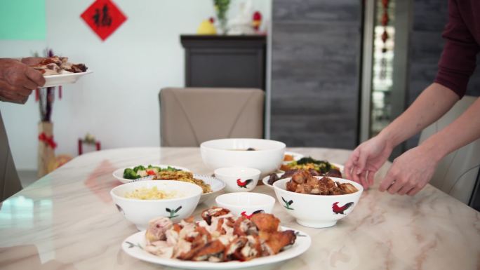 春节期间，亚裔中国年轻人和父亲一起把食物放在餐桌上