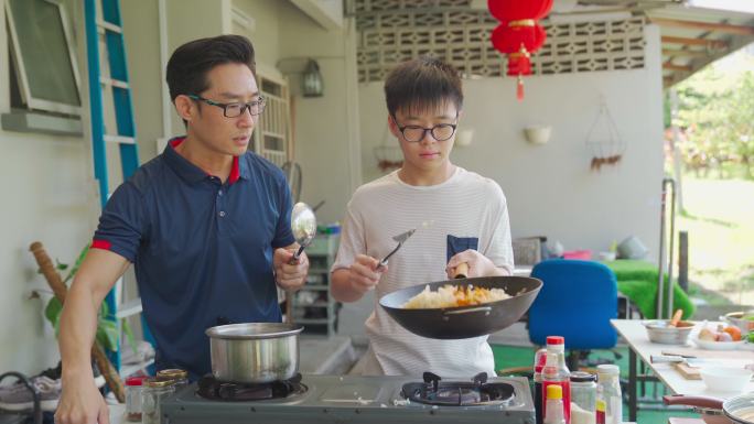 周末，亚裔中国父亲和儿子在潮湿的厨房后院一起做饭准备晚餐