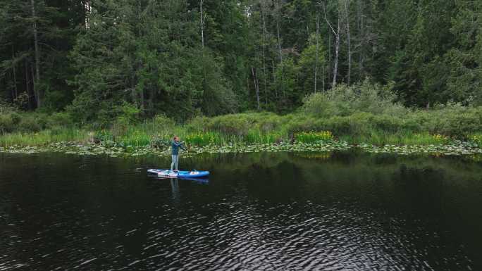 中年女性在一个原始的湖面上划桨度假