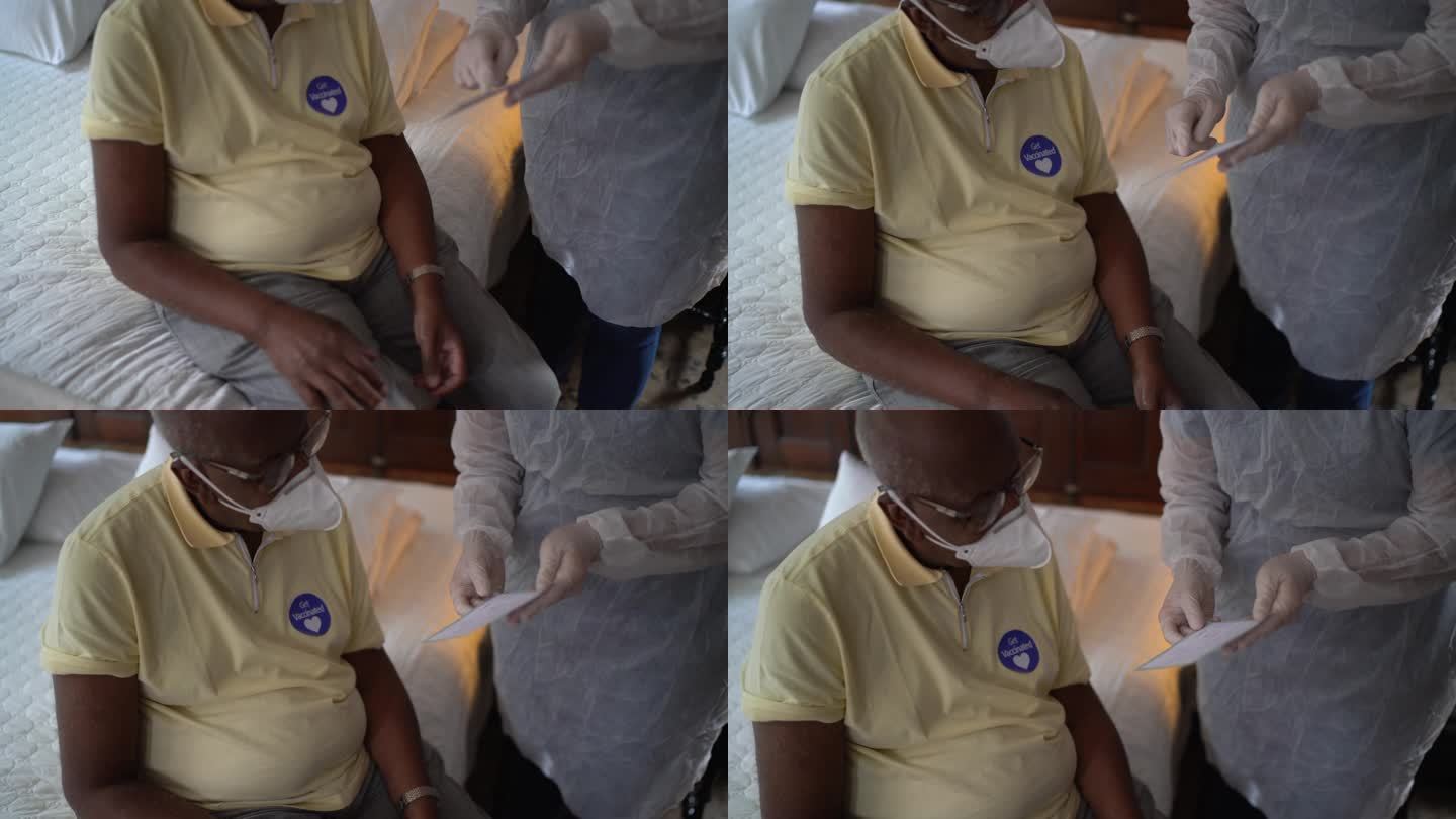 医生给家里的老人发放免疫疫苗证书-戴口罩