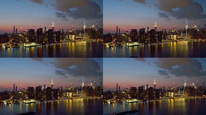 日落时分，纽约市曼哈顿中城东河对岸的远处全景夜景。向后移动摄像机的空中视频。