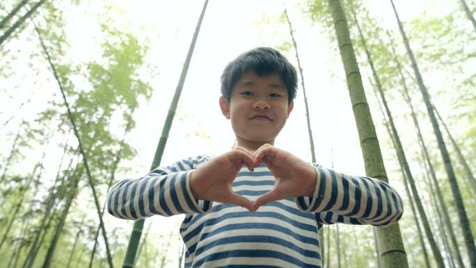 小男孩在竹林中展示心形