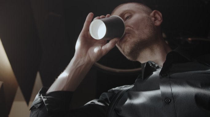 一名身穿黑色衬衫的男子在窗前喝咖啡的肖像