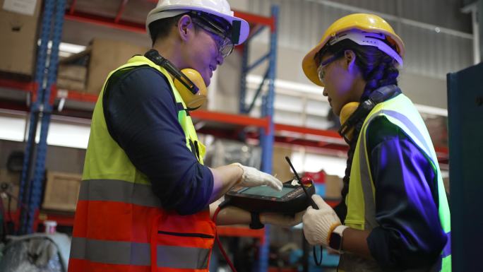 员工们在工厂里用机器人手臂工作。
